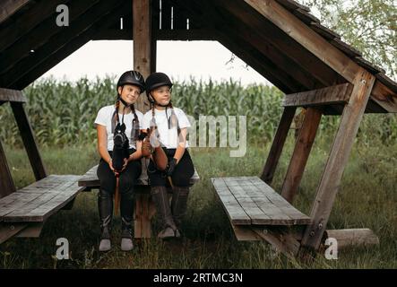 Porträt von Mädchen Jockeys, die auf einem Holztisch unter einem Baldachin sitzen. Stockfoto