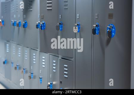 Abschließbare Staufächer für Taschen und Rucksäcke an öffentlichen Orten. Graue Fächer, teilweise geöffnet, blaue Nummern und Schlüssel an den Türen. Stockfoto