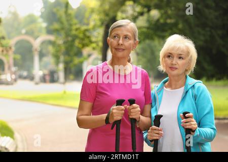 Zwei Seniorinnen mit Nordic Walking-Stangen im Freien, Platz für Text Stockfoto