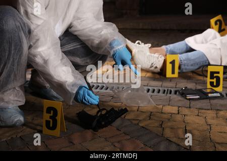 Kriminologe in Schutzhandschuhen, die am Tatort mit Leichen im Freien arbeiten, Nahaufnahme Stockfoto