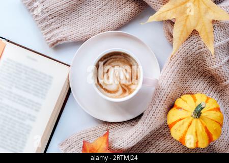 Heißer Kaffee in einer Tasse, ein offenes Buch, gelber Kürbis und Herbstblätter. Draufsicht, flach. Herbstkonzept. Stockfoto