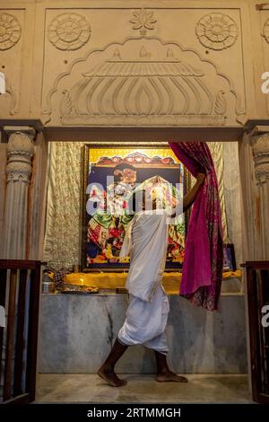 Priester zieht den Vorhang in einem Tempel im Goverdan Ecovillage, Maharashtra, Indien Stockfoto