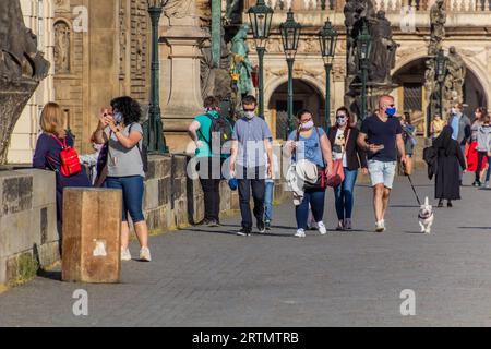 PRAG, TSCHECHIEN - 27. APRIL 2020: Maskentragende Menschen überqueren die Karlsbrücke in Prag während der COVID-19-Sperre in der Tschechischen Republik. Stockfoto