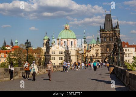 PRAG, TSCHECHIEN - 27. APRIL 2020: Maskentragende Menschen überqueren die Karlsbrücke in Prag während der COVID-19-Sperre in der Tschechischen Republik. Stockfoto