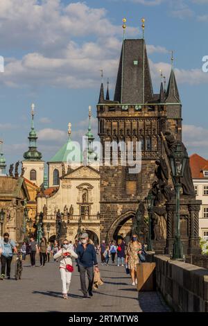 PRAG, TSCHECHIEN - 27. APRIL 2020: Maskentragende Menschen überqueren die Karlsbrücke in Prag während der COVID-19-Sperre in der Tschechischen Republik. Stockfoto