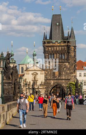 PRAG, TSCHECHIEN - 27. APRIL 2020: Maskentragende Menschen überqueren die Karlsbrücke in Prag während der COVID-19-Sperre in der Tschechischen Republik. Stockfoto