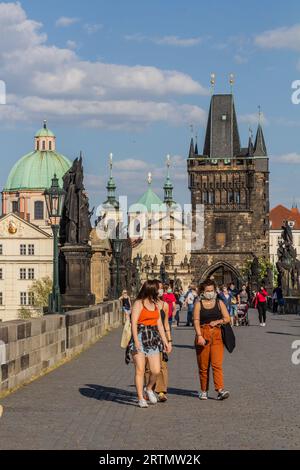 PRAG, TSCHECHIEN - 27. APRIL 2020: Maskentragende Menschen überqueren die Karlsbrücke in Prag während der COVID-19-Sperre in der Tschechischen Republik. Stockfoto