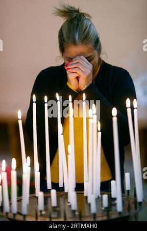 Katholische Frau betet in einer Kirche vor brennenden Kerzen. Glaube und Religion. Frankreich. Stockfoto