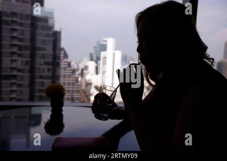 Silhouette einer eleganten jungen Frau, die ein Glas Champagner in einer 5-Sterne-Lounge-Bar des Hotels trinkt. Bangkok. Thailand. Stockfoto