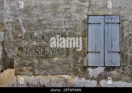 Vintage-Werbung auf einer rustikalen Wand neben einem blauen Fenster. Crécy-la-Chapelle, Frankreich. Stockfoto