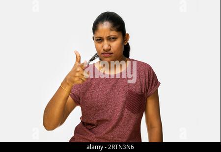 Ein Nahaufnahme-Porträt einer jungen Frau, die mit dem Finger auf die Kamera auf weißem Hintergrund zeigt Stockfoto