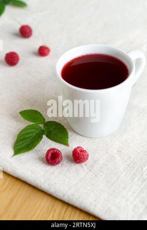 Süßes, erfrischendes Beerenkompott aus Reifen Himbeeren in einer weißen Tasse, reichhaltiger Geschmack, gesättigte Farbe. Frisches saisonales Getränk Stockfoto