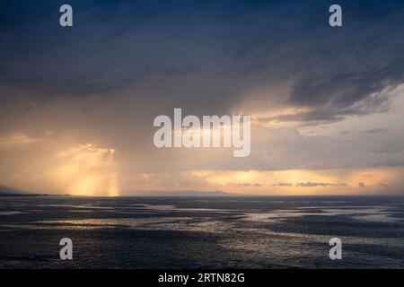 Sonnenuntergangslandschaft zwischen den Wolken über dem Horizont des Meeres. Goldene Reflexionen in den Wolken und im Meer. Stockfoto