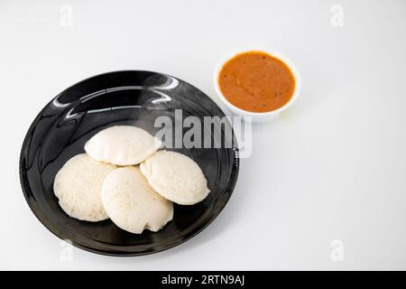 Heiß und gleichmäßig in einer schwarzen Platte und Tomaten-Chutney auf einem isolierten weißen Hintergrund. Dampfend heiß und rot chutny isoliert. Gesunde Ernährung / B Stockfoto