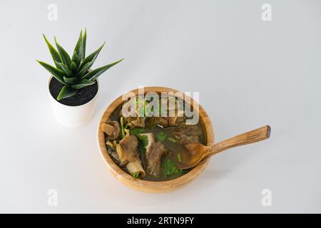 Frisch gewürzte Lammsuppe in einer Holzschüssel, verzehrfertig. Hausgemachte Hammelsuppe namens paya oder attukaal Suppe in südindien. Hammelsuppe aus Holz Stockfoto