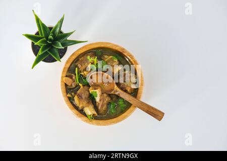 Frisch gewürzte Lammsuppe in einer Holzschüssel, verzehrfertig. Hausgemachte Hammelsuppe namens paya oder attukaal Suppe in südindien. Hammelsuppe aus Holz Stockfoto