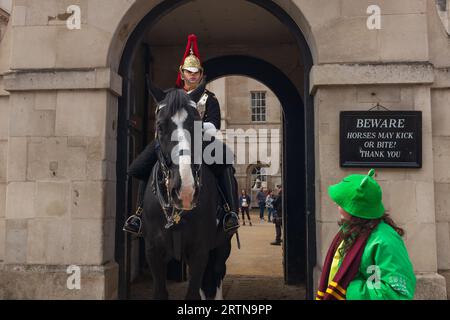 London, Großbritannien, 2023. Ein junges Mädchen im Froschgrün-Outfit spricht mit einer Pferdewache vor dem Household Cavalry Museum in der Parliament Street Stockfoto