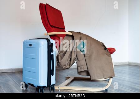 Übersetzung: "Militärische ID". Reisetasche steht neben rotem Sessel mit Mantel. In der Tasche befindet sich ein Dokument Stockfoto