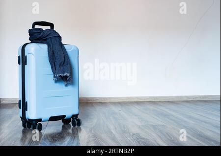 Blaue Reisetasche auf Rädern mit Schal um den Griff. Copyspace, Hintergrund Stockfoto