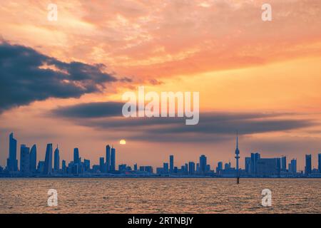 Blick auf die Skyline von Kuwait - mit dem bekanntesten Wahrzeichen von Kuwait City - bei Sonnenuntergang Stockfoto