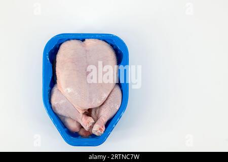 Ganzes rohes Huhn mit Haut, verpackt in einer Kunststoffbox und zur Lagerung verschlossen. Rohes Huhn mit Hauttasche zum Kochen. Stockfoto