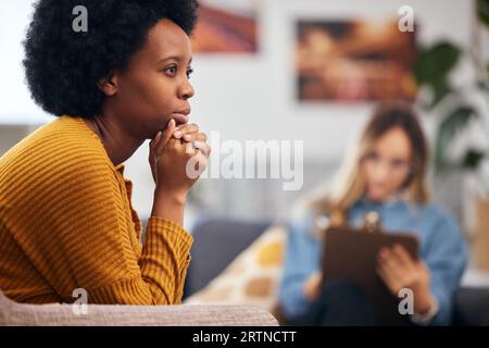 Psychische Gesundheit, Angst und Psychologie mit einer schwarzen Frau in der Therapie, im Gespräch mit einem Profi. Depression, Stress oder Unterstützung bei einem jungen Patienten in Stockfoto
