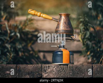 Kupferzesve auf Gasbrenner in der Natur. Kaffeezubereitung unter Feldbedingungen Stockfoto