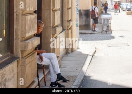 Havanna, Kuba - 30. August 2023: Kubanischer Seniormann sitzt auf einem Stuhl auf dem Bürgersteig Stockfoto