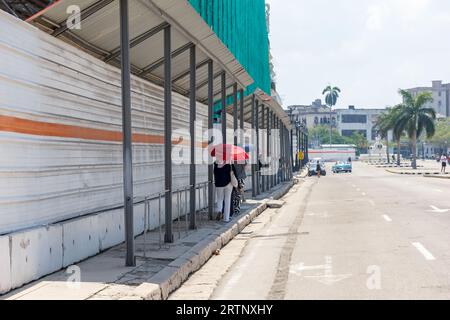 Havanna, Kuba - 30. August 2023: Kubanische Menschen laufen am Zaun auf einer Baustelle im Stadtzentrum. Stockfoto