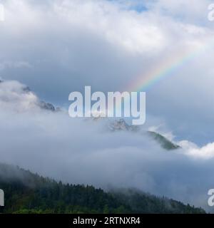 Ein Regenbogen über einem Berggipfel, der im Triglav-Nationalpark in Slowenien von Wolken umgeben ist Stockfoto