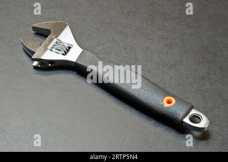 Verstellbarer Schraubenschlüssel mit Messwerkzeug auf schwarzem Holztisch Stockfoto