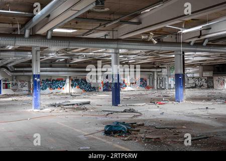 Ein verlassenes und verwüstetes Industriegebäude mit Graffitis an der Wand und Trümmern auf dem Boden in Paimio, Finnland Stockfoto