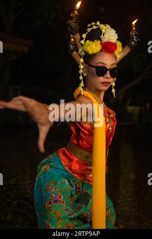 Eine javanische Tänzerin tanzt sehr geschickt, während sie eine Sonnenbrille auf den Augen trägt und nachts ein sehr schönes Gesichts-Make-up trägt Stockfoto