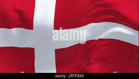 Dänische Nationalflagge weht an einem klaren Tag. Rote Flagge mit einem weißen skandinavischen Kreuz, das sich bis zum Rand der Flagge erstreckt. 3D-Illustrations-Rendering. Flutt Stockfoto