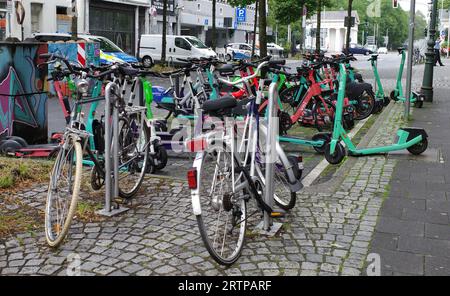 Düsseldorf, Deutschland - 2. August 2023 E-Scooter werden chaotisch zwischen Fahrrädern geparkt. Sie stammen aus Tier, Check und VOI. Stockfoto