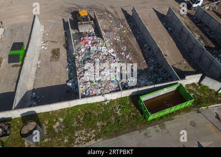 Radlader, der auf Mülldeponien eingesetzt wird, Abfallmaterial mit einer Schaufel transportiert und entsorgt, Luftaufnahme aus einem großen Winkel. Stockfoto