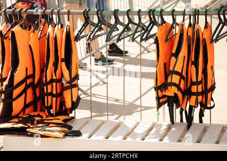 Schwimmwesten hängen in der Sommersonne in der Nähe des Flusses auf Kleiderbügeln auf der Straße Stockfoto