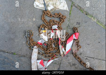 Blick hinunter auf eine alte, rostige, schwere Metallsicherheitskette, die auf dem Boden aufgegeben wurde Stockfoto