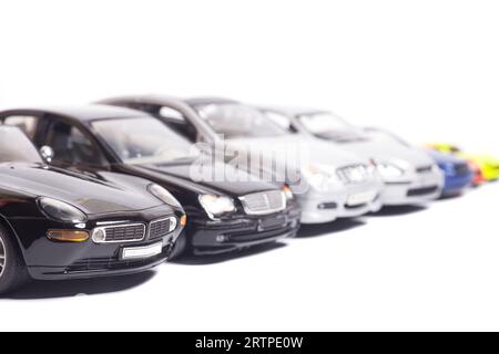 Spielzeugautos in einer Reihe isoliert auf weiß parken. Stockfoto