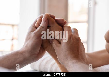 Fußreflexzonenmassage. Männlicher Masseur führt Akupressur am Fuß einer Frau durch. Leuchtender Hintergrund. Selektiver Fokus. Stockfoto