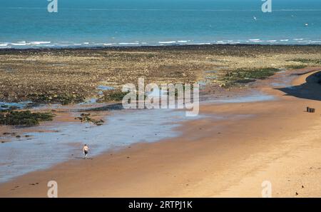 Unbekannte Person, die am Sandstrand spaziert. Gesunder Lebensstil. Draußen trainieren. Stockfoto