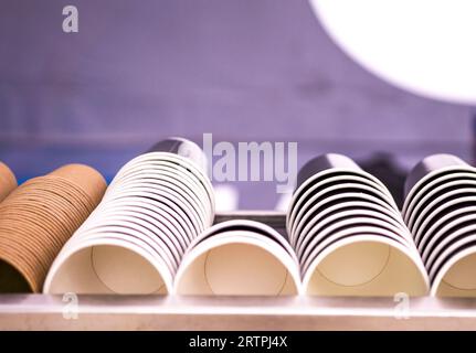 Die Ränge der Papierkurben. Kaffeegläser. Wand aus Tassen aus Pappe. Kunststoffbecher, Deckel, Strohhalme, Röhrchen Stockfoto