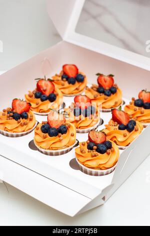 Orange Cupcakes mit frischen Beeren und Buttercreme in der Geschenkbox Stockfoto