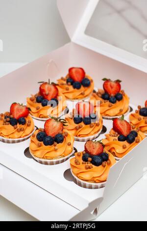 Orange Cupcakes mit frischen Beeren und Buttercreme in der Geschenkbox Stockfoto