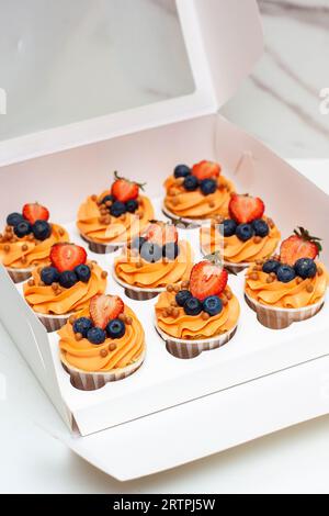 Orange Cupcakes mit frischen Beeren und Buttercreme in der Geschenkbox Stockfoto