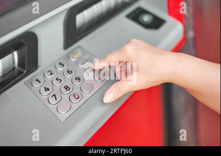 Hand einer anonymen Person, die die geheime Nummer in den Geldautomaten der Bank eingibt, um sich zu identifizieren und Geld abheben zu können. Stockfoto