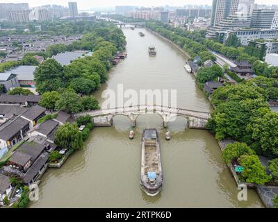 Hangzhou. 27. Mai 2022. Dieses Luftbild vom 27. Mai 2022 zeigt ein Frachtschiff, das den Peking-Hangzhou-Canal in Hangzhou, der ostchinesischen Provinz Zhejiang, entlang segelt. Die 19. Asienspiele finden vom 23. September bis zum 8. Oktober in Hangzhou statt und umfassen insgesamt 40 Sportarten. Nach Peking 1990 und Guangzhou 2010 werden die Asienspiele zum dritten Mal in China ausgetragen. Die mit Spannung erwarteten Asienspiele können dazu beitragen, die Popularität von Hangzhou zu steigern, wo Geschichte und Moderne nebeneinander existieren, und seine Kultur weiter zu fördern. Quelle: Jiang Han/Xinhua/Alamy Live News Stockfoto