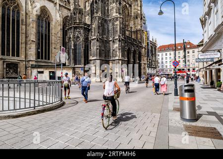 Wien, Österreich. Blick auf die Nordseite des Stephansplatzes und der St. Stephansdom. Eine Frau fährt durch den Platz. 2023-08-02. Stockfoto