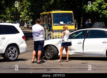 Der Mann und die Frau reden nach einem schweren Verkehrsunfall. Zwei Fahrer streiten sich nach einem Verkehrsunfall auf der Straße. Autounfall auf der Straße. Konzept fehlgeschlagen Stockfoto