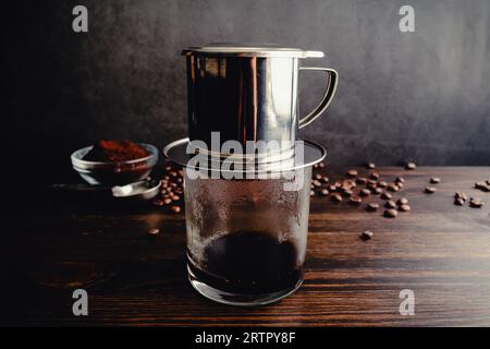 Brühen von heißem vietnamesischem Schwarzkaffee (Cà Phê den) mit einem Phin-Filter: Vietnamesischer Kaffee wird mit einem Tropffilter zubereitet Stockfoto